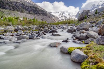 Stream flowing through rocks against sky