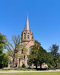 Low angle view of trees and building against sky