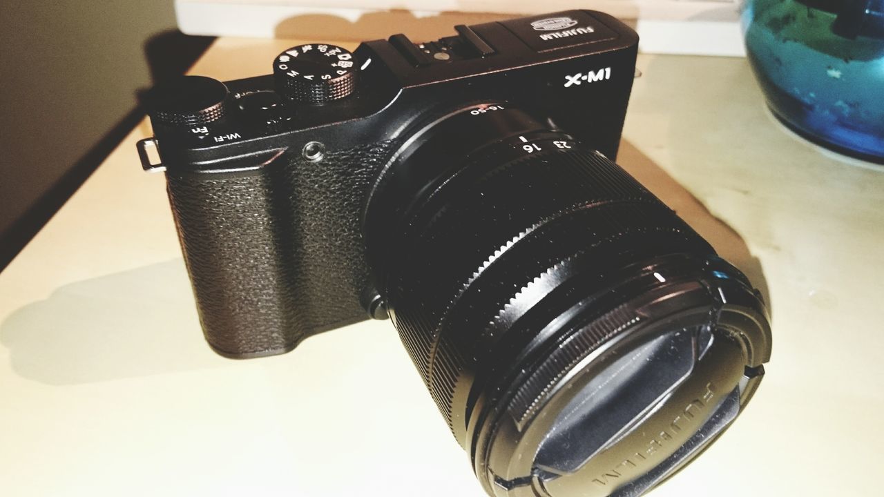 indoors, close-up, technology, still life, table, high angle view, old-fashioned, no people, retro styled, black color, arts culture and entertainment, focus on foreground, low angle view, music, metal, camera - photographic equipment, single object, photography themes, reflection, day