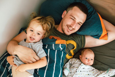 Young man lying in bed with kids