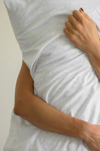 Cropped hand holding pillow against white background