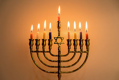 Close-up of illuminated lamp against orange background