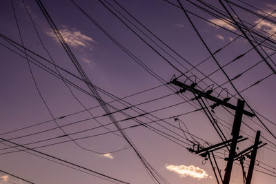 Low angle view of silhouette electricity pylon against sky at sunset