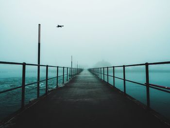 Empty pier over river during foggy weather