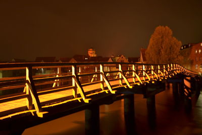 Illuminated bridge in city against sky at night