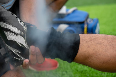 Cropped hand holding man leg on soccer field