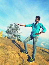 Optical illusion of man touching tree while standing against sky