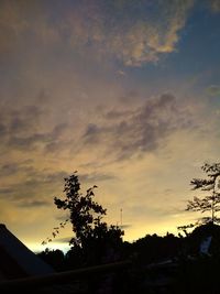 Low angle view of silhouette tree and building against sky during sunset