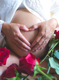 Midsection of pregnant woman with flowers