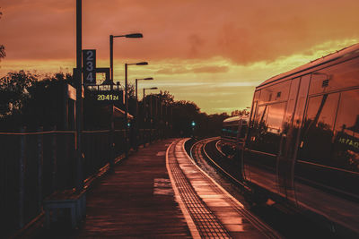 Train on railroad tracks against sky during sunset