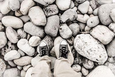 Low section of man standing on pebbles