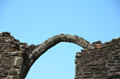 Low angle view of old ruins against clear blue sky