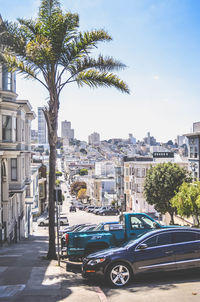 Road by buildings in city against sky