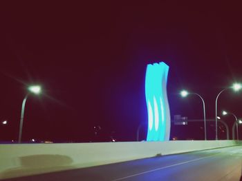 Illuminated street light against sky at night