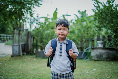 Portrait of boy standing against plants