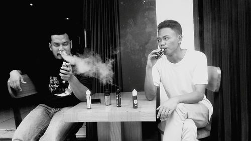 Young man smoking cigarette while sitting on table