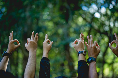 People with arms raised gesturing outdoors