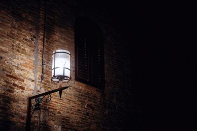 Low angle view of illuminated lamp on wall