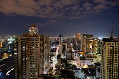 Illuminated buildings in city against sky at night