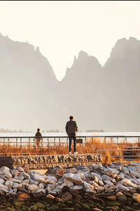 Man standing on rock against sky