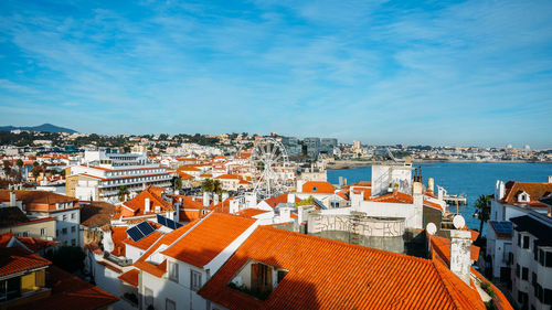 High angle view of townscape by sea against blue sky