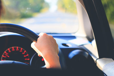 Cropped hand of woman driving car