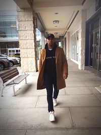 Full length portrait of young man standing against building