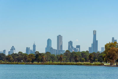 Scenic view of river by buildings against clear sky