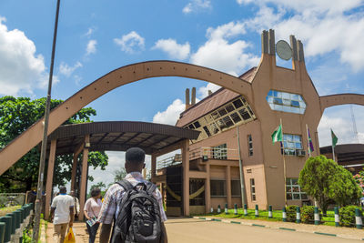 Rear view of people walking on bridge against sky