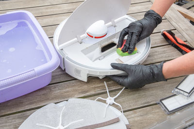 Woman washing a trash can in a robot vacuum cleaner, planned maintenance