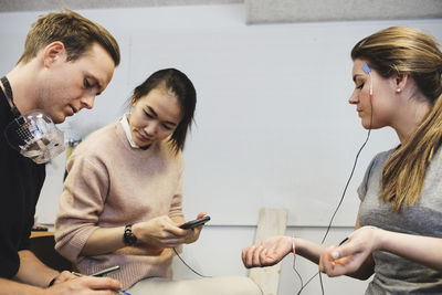 Engineers checking workout app on woman in office