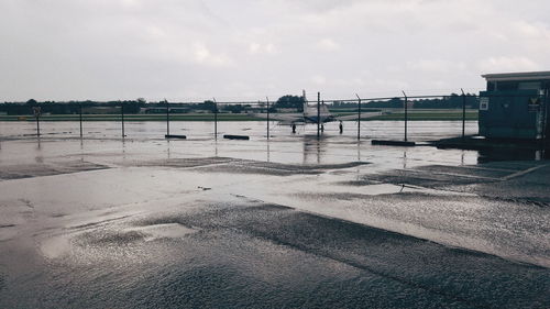 Airplane stationary at wet airport against sky in city