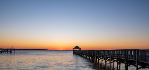 Pier over sea against sky during sunset