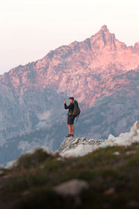 Full length of man standing on rock in mountains against sky