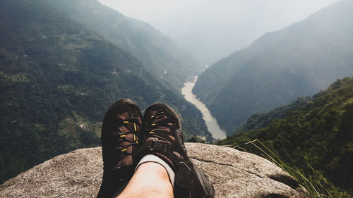 Low section of man standing on mountain against sky