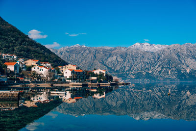 Reflection of buildings in lake against blue sky