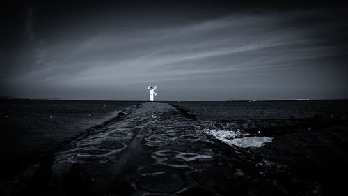 Lighthouse by sea against sky