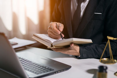 Midsection of man reading book while sitting on table