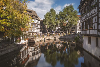 Canal amidst trees and buildings against sky