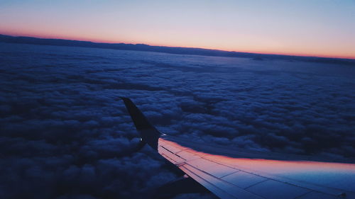 Aerial view of aircraft wing over sea during sunset