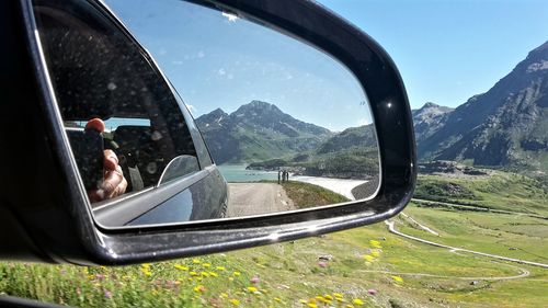 Mountain reflecting in side-view mirror of car