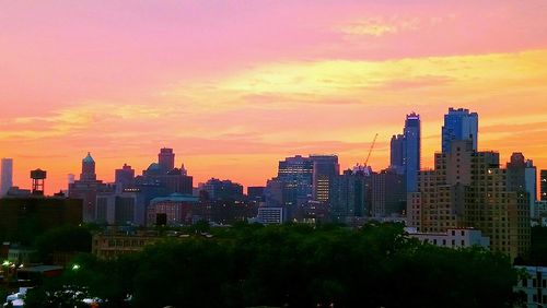 Modern buildings in city against sky during sunset