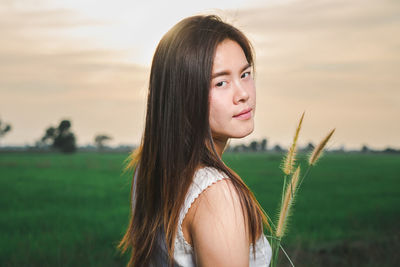 Portrait of beautiful woman holding plants during sunset