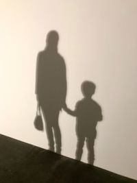 Shadow of father with son walking against clear sky