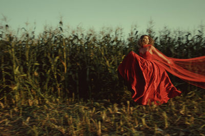 Woman wearing red dress standing amidst plants