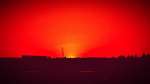 Silhouette of factory against clear sky during sunset