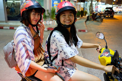Portrait of smiling women on scooter in city