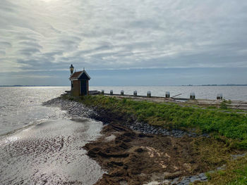 Lighthouse by sea against sky