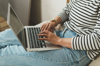 Beautiful woman is sitting at home and working on a laptop.