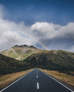 Empty road by mountains against sky